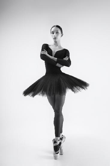 schwarzer Schwan. Ballerina im schwarzen Tutu zeigt Elemente des Balletttanzes in Bewegung