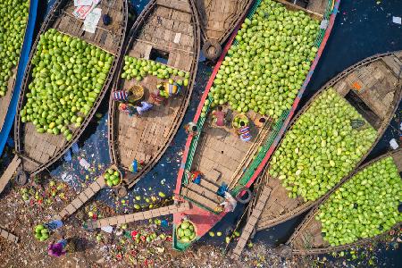 Arbeiter laden Wassermelonen mit großen Körben von den Booten