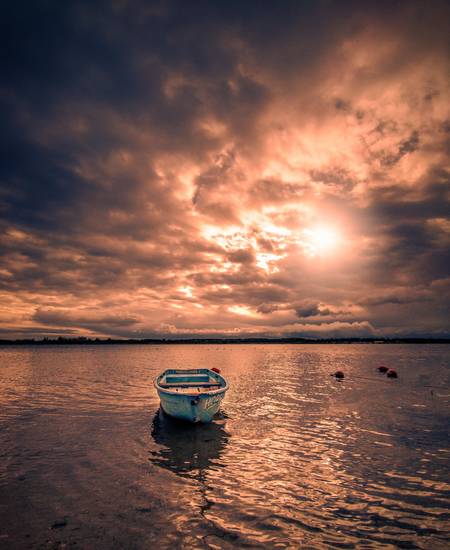 verlassenes Boot am See mit Sonnenschein und Wolken 2021