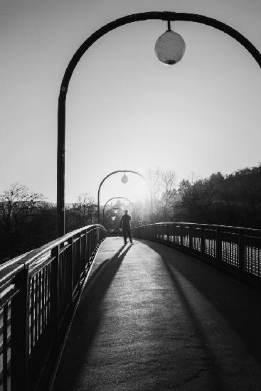 Mann im Gegenlicht auf einer Brücke