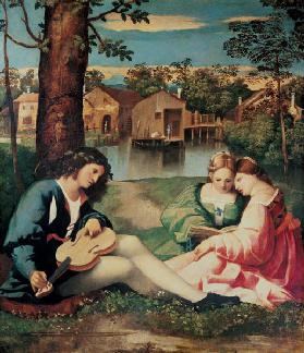 Youth with a guitar and two girls sitting on a river bank