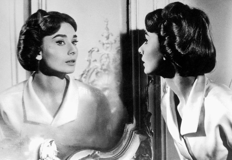 Actress Audrey Hepburn looking at her reflection in the mirror von 