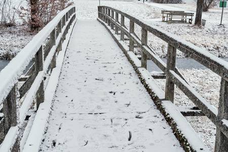 verschneite kleine Holzbrücke über einem Bach 2022