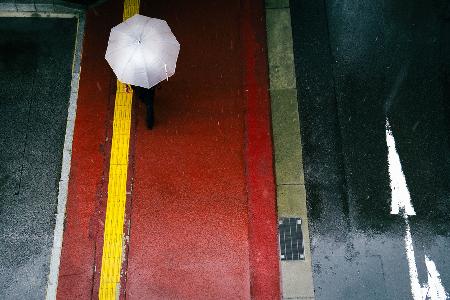 Der rote Bürgersteig und ein weißer Regenschirm
